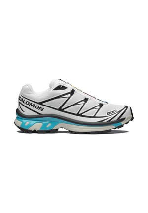 Zapatilla de running Salomon blanca y negra con suela azul y beige, detalles geométricos negros y sistema de cordones rápidos sobre fondo blanco.