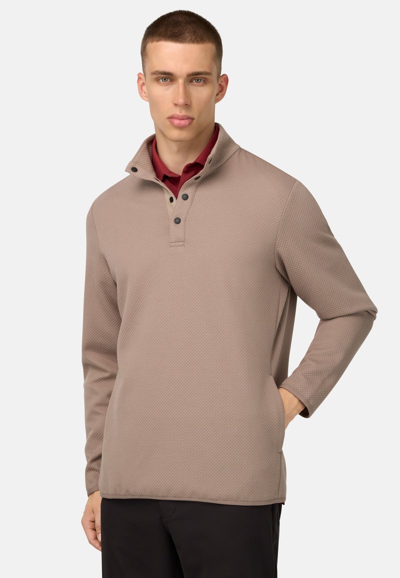 Maglione marrone texturizzato con colletto alto, dotato di una patta con bottoni e maniche lunghe, indossato sopra una camicia bordeaux.