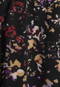 Kwiatowy czarny materiał z czerwonymi, purpurowymi i złotymi wzorami o teksturowanej powierzchni. Projekt zawiera mieszankę abstrakcyjnych kształtów i kolorów.