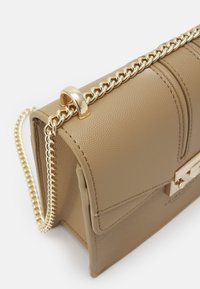 Borsa a tracolla in pelle marrone chiaro con finitura testurizzata, design a strati, tracolla in catena dorata e una grande chiusura in metallo dorato.