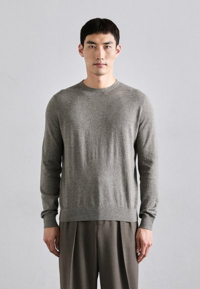 Grå langærmet sweater med rund halsudskæring, fremstillet af et blødt, struktureret materiale. Har ribbede manchetter og kant, båret over beige bukser.