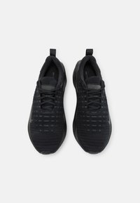 Pár černých sportovních tenisek s tkaničkami a poutky, pohled shora na bílém pozadí.