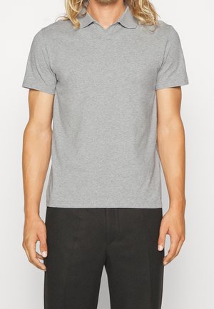 Szara bawełniana koszulka polo z krótkim kołnierzykiem, krótkimi rękawami i dopasowanym krojem, zestawiona z czarnymi spodniami. Gładka faktura, minimalne zdobienia.