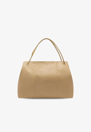 Beżowa skórzana torebka o zaokrąglonym trapezowym kształcie, z dwoma cienkimi rączkami i złotym akcentem przy jednej z nich na białym tle.