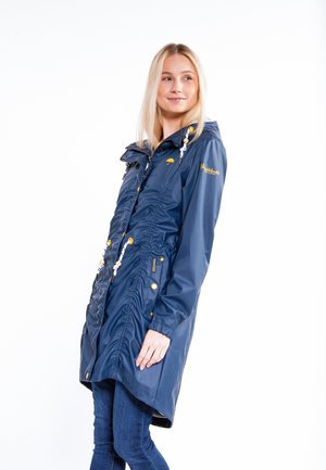 Marineblauwe waterdichte jas met een getailleerde taille, capuchon, gouden hardware en trekkoordaccenten; heeft ritszakken en logo-detail.