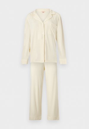 Haut de pyjama crème à manches longues, boutonné, avec poche poitrine, et pantalon de pyjama long assorti sur fond uni.