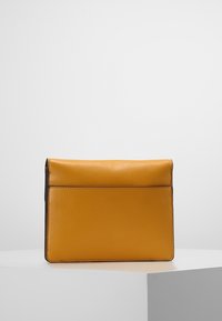 Borsa a mano in pelle gialla con una forma strutturata, pattina pieghevole e una texture liscia. Presenta un design minimalista e senza hardware visibile.