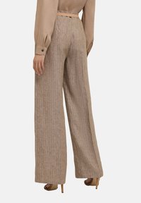 Beiga byxor med vida ben och vertikala ränder, tillverkade av ett strukturerat tyg. Har ett bälte och hög midja med en lös passform.