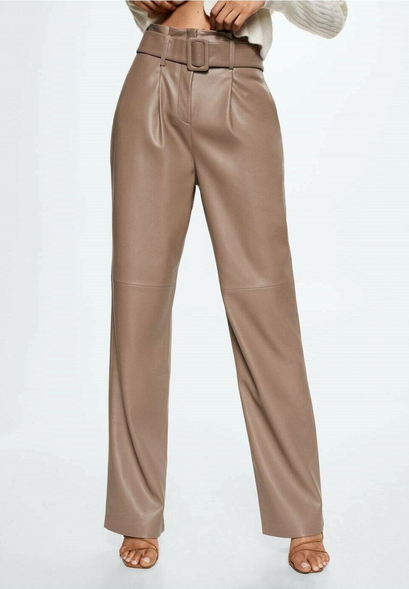 Pantalon en cuir taupe taille haute avec une large boucle de ceinture, jambes droites, porté avec des talons ouverts et un haut blanc à manches longues.