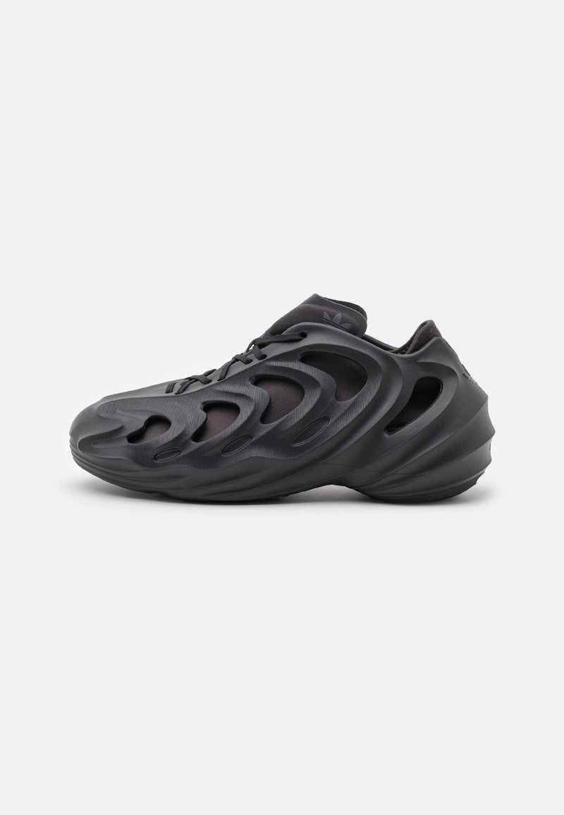 Black athletic shoe with a unique curved design, textured surface, and cut-out sections for ventilation. Features laces and logo detail.