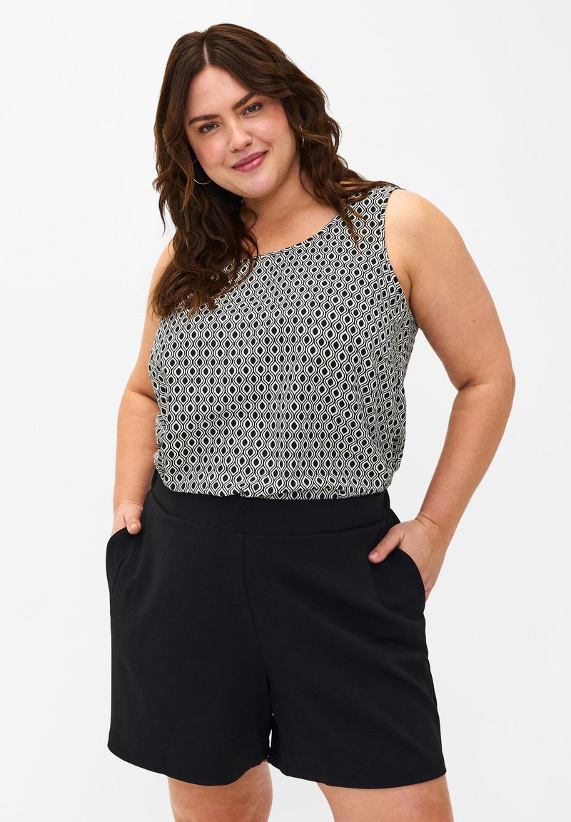 Pantaloni corti neri con cintura elastica, abbinati a una maglietta senza maniche con un motivo geometrico in bianco e nero.