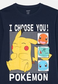 Mornarsko plava majica s nasmijanim Pikachuom i licima Charmandera, Bulbasaura i Squirtlea, s natpisom "Birajem te! Pokémon".