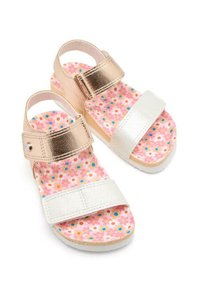 Sandalias metálicas en color rosa dorado y blancas con una plantilla de color rosa con un patrón floral. Presentan correas ajustables y una suela plana texturizada.
