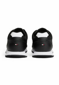 Schwarze Sportschuhe mit einem Obermaterial aus Leder und Netzgewebe, weißen Akzenten und einem kleinen Logo-Patch an der Ferse. Dicke Gummisohle für besseren Halt.