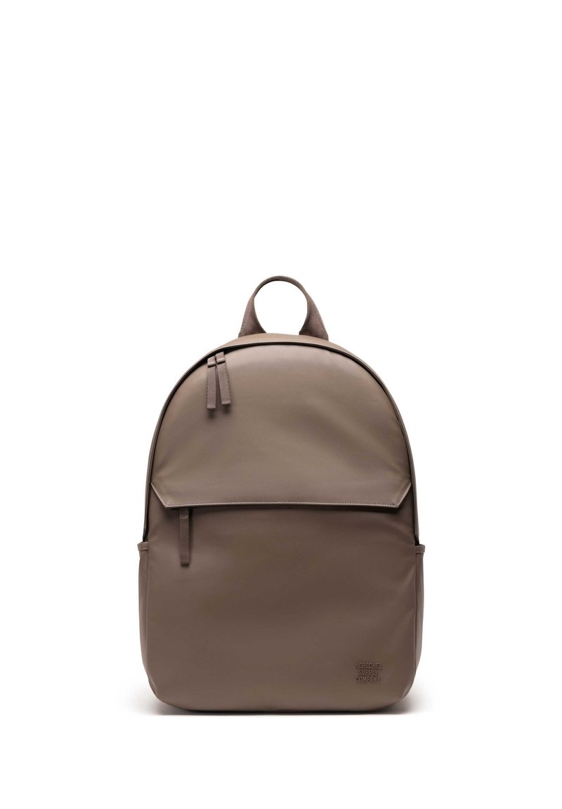 Brown backpack made of smooth, durable material. Features a rounded shape, front flap, zipper, and a top carrying handle. Minimalist design.