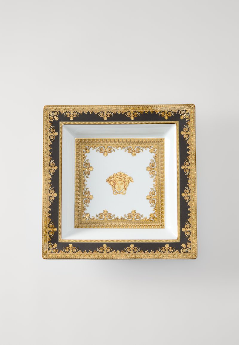 Kvadrātveida porcelāna šķīvis ar melnu un zeltu ornamentālu maliņu, centrā ar Medūzas motīvu, ko ieskauj izsmalcinātas zelta detaļas.