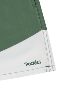 Grønne og hvite svømmedraktshorts med en glatt tekstur, med et buet farveblokkdesign og trykk av merkevaren "Pockies" nær kanten.