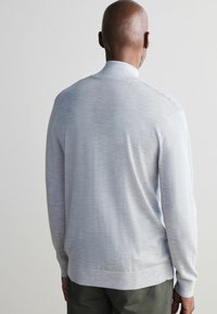 Hellgrau gestrickter Pullover mit Kragen, nahtlosem Design und leicht strukturiertem Stoff, mit langen Ärmeln und geripptem Saum.