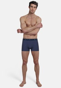 Navy blue boxer briefs with a horizontal striped pattern, featuring an elastic waistband with "bugatti" logo. Made from soft, stretchy fabric.