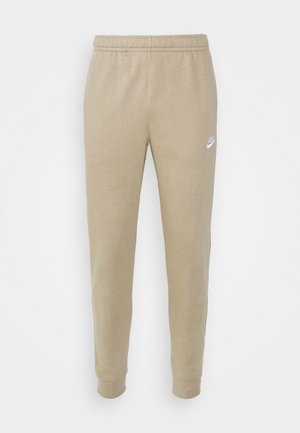 Beige Nike sweatpants med elastisk talje, tapered ben og hvidt logo på venstre lår. Blødt bomuldsstof med en glat tekstur.
