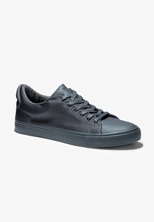 Zapatillas de deporte gris oscuro con parte superior de tela de malla, suela de goma y cordones planos. Presentan una punta redondeada y paneles laterales texturizados.