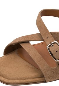 Καφέ σαμουαγιά σανδάλι με σταυρωτούς ιμάντες και ασημένια αγκράφα. Διαθέτει λεία εσωτερική σόλα και υφασμένη εξωτερική επιφάνεια.