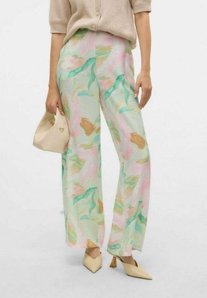 Pantalones de pierna ancha con estampado floral en colores pastel (verde, rosa, beige) con un acabado texturizado, combinados con un bolso crema y zapatos de punta.