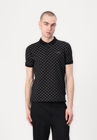 Svart polo skjorte med geometrisk mønster i sølvtoner, korte ermer og krage i klassisk stil. Brodert logo på brystet.