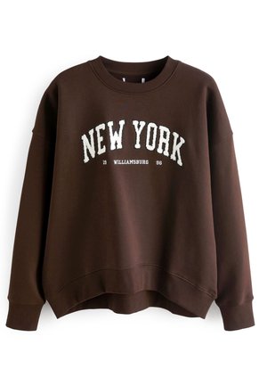 Dark brown crewneck sweatshirt with white "NEW YORK" text arched on front, smaller "WILLIAMSBURG 1996" text underneath, long sleeves, ribbed cuffs.