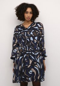 Gemustertes Kleid mit V-Ausschnitt, langen Ärmeln, elastischem Taillenzug und fließender Silhouette. Es hat blau, schwarz und beige gewundene Designs auf leichtem Stoff.