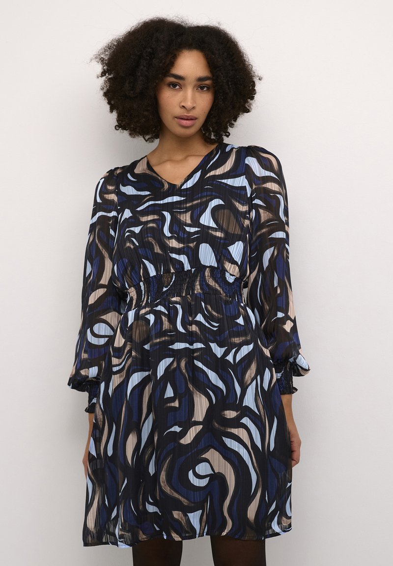 Gemustertes Kleid mit V-Ausschnitt, langen Ärmeln, elastischem Taillenzug und fließender Silhouette. Es hat blau, schwarz und beige gewundene Designs auf leichtem Stoff.