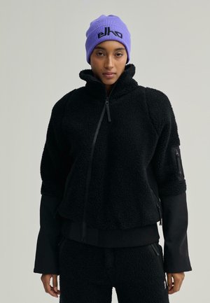 Zwarte fleecjas met hoge kraag, ritssluiting en ribgebreide manchetten. Gepaard met zwarte fleece broek. Paarse gebreide beanie met logo-detail.
