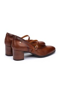 Chaussures à talons en cuir marron avec un bout arrondi, une bride au niveau de la cheville et un talon en bois. Présente une texture crocodile subtile à l'arrière.