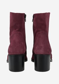 Bottines en suède bourgogne avec un talon noir de hauteur intermédiaire, dotées d'une fermeture éclair sur le côté et d'une texture lisse. Aucun motif ou accent visible.