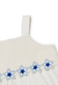 Weißes Baumwollkleid mit einem strukturierten Oberteil, das mit einem gehäkelten hellblauen Saum verziert ist, der mit sternförmigen Mustern und blauen Mittelpunkten geschmückt ist.