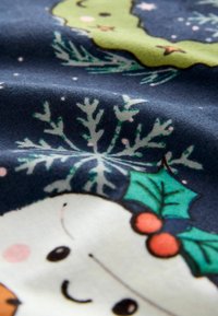 Bomuldsstof med en mørkeblå baggrund og glade illustrationer af snefnug og julemotiver, herunder en snemands og mistelten detaljer.