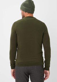 Maglione a coste verde oliva con maniche lunghe e scollo rotondo, abbinato a pantaloni grigio scuro. Dettagli a coste sui polsini e sull'orlo.