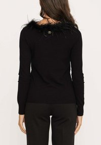 Zwarte trui met een textuur van bont aan de kraag, lange mouwen en een geribbelde zoom, gecombineerd met een op maat gemaakte zwarte broek. Achteraanzicht weergegeven.