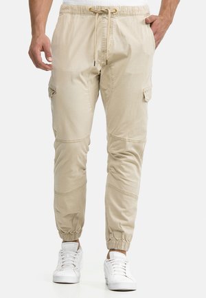 Beige cargo-joggers lavet af letvægtsstof, med elastisk taljebånd og snøre, sidelommer og elastiske ankelmanchetter.