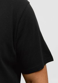Czarny krótki rękaw t-shirt wykonany z miękkiej bawełny, z okrągłym dekoltem i gładką fakturą. Czysty, minimalistyczny design bez wzorów czy akcentów.