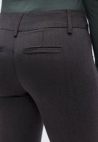 Γκρι παντελόνι προσαρμοσμένο με ομαλή υφή, μεσαία μέση και δύο πίσω τσέπες. Το ύφασμα έχει ένα διακριτικό, λεπτό μοτίβο ύφανσης.