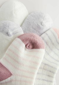 Sæt af fem strømper i forskellige farver: creme, lys grå, pink, med teksturer som rib og striber; rund tå og hælform.