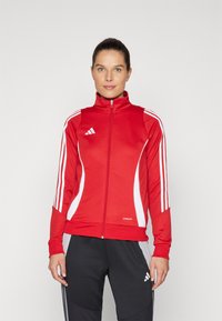 Red athletic jacket with white accents and zipper. Features three white stripes on each sleeve, made from lightweight, moisture-wicking fabric.