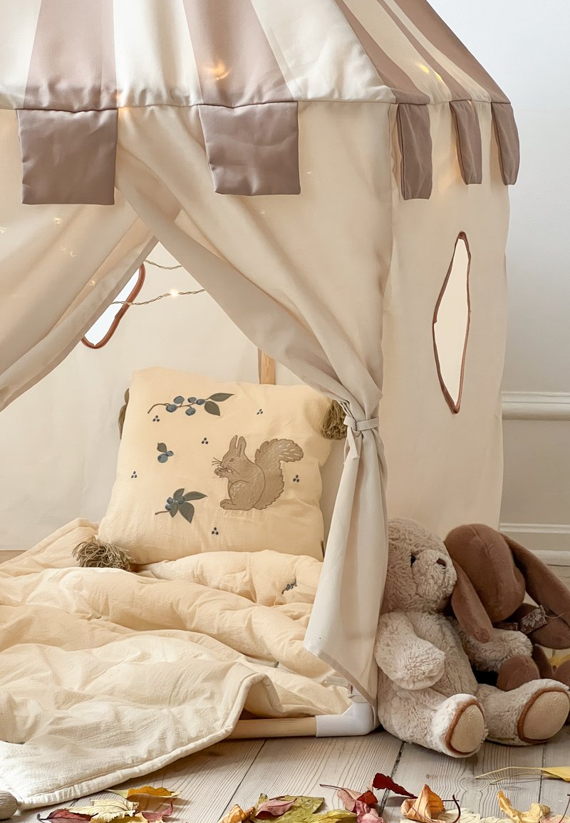Σπιτάκι παιχνιδιού σε σχήμα τέντας με μπεζ ύφασμα και απαλές ροζ ρίγες. Περιλαμβάνει μαξιλάρι με σχέδιο σκούρου, ζεστή κουβέρτα και λούτρινα παιχνίδια.