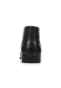 Botte de cheville en cuir noir avec une texture lisse, un orteil arrondi, un talon renforcé et un talon bas astiqué ; présente des coutures sur les côtés.