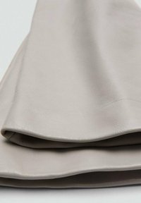 Material de imitación cuero gris doblado, con una textura suave y un grano sutil, resaltando la naturaleza suave y flexible de la tela.