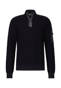 Svart tröja med strukturstickning, halvdragkedja och en patchficka på vänster ärm. Ribbade ärmslut och nederkant.