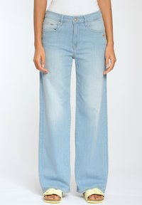 Světlemodré džíny s širokými nohavicemi vyrobené z denimu, s vysokým pasem, pěti kapsami a jemným vyblednutím. Pásky pro opasek jsou viditelné na pase.