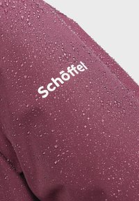 Wasserabweisender kastanienbrauner Stoff mit Tropfen, versehen mit einem sichtbaren weißen "Schöffel"-Logo auf der Schulter. Glatte Textur und elegantes Design.