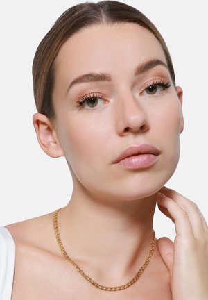 Gouden ketting met een schakeldesign, rustend op de huid. Gladde textuur met een glanzende afwerking. Model poseert met hand op de nek.